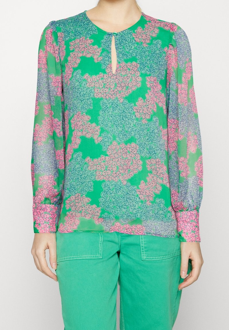 Blusa a maniche lunghe in tessuto trasparente verde con motivo floreale in rosa e blu. Presenta un collo a chiave e polsini delle maniche arricciati.