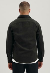 Donkergroen flanellen shirt met een kraag, lange mouwen en knoopmanchetten; gladde textuur met subtiele kleurnuances.