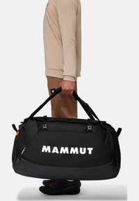Borsa a cilindro nera con logo "MAMMUT" in bianco. Realizzata in materiale resistente, presenta manici robusti e fibbie. Superficie testurizzata, design elegante.