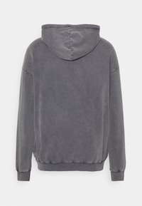 Sudadera con capucha gris, que presenta una textura suave, puños y cinturilla acanalados. La vista trasera muestra un diseño sin costuras y sin logotipos visibles.