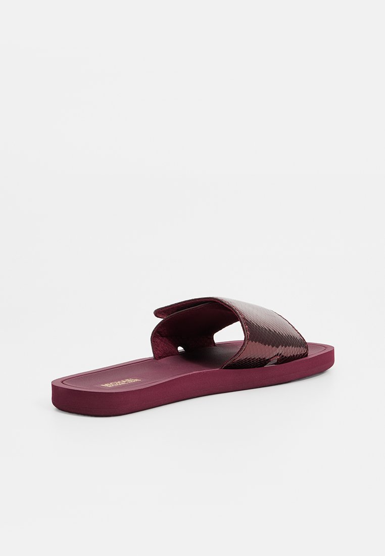 Burgundowe sandały na płaskiej podeszwie z teksturowaną syntetyczną cholewką. Otwarty nosek i szeroki pasek zapewniający pewne trzymanie.