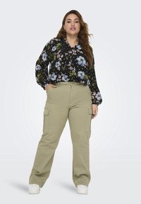 Svart blommig blus med långa ärmar, prydd med blå blommor och gröna blad. Olivgröna cargobyxor med sidofickor, kombinerat med vita sneakers.