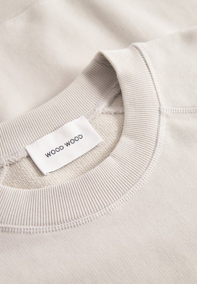 Hellgrau Sweatshirt mit geripptem Rundhalsausschnitt. Verfügt über eine glatte Textur und ein Stofflabel mit der Aufschrift "WOOD WOOD."