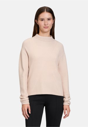 Pull en maille ribbed rose pâle avec des manches longues et un col haut, présentant des motifs diagonaux et des poignets froncés pour une texture supplémentaire.