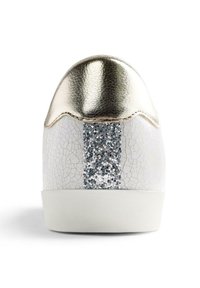 Sneaker bianca con una texture screpolata, tacco metallico dorato e una striscia di glitter argento sul retro. Presenta una suola bianca.