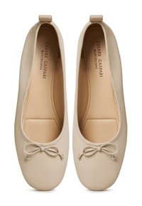 Ballerine in pelle beige con punta arrotondata, un piccolo fiocco decorativo e una fodera interna liscia, caratterizzate da un design minimalista.