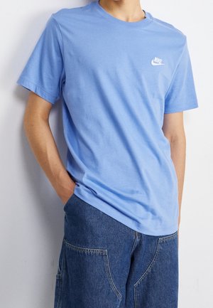 Jasnoniebieska bawełniana koszulka z krótkim rękawem, okrągłym dekoltem i małym białym logo Nike na lewej piersi. W połączeniu z dżinsowymi spodniami.