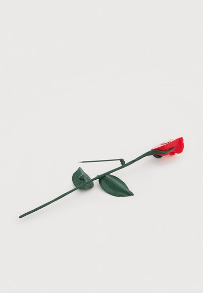 Broche en métal en forme de rose rouge avec tige et feuilles vertes, montrant le mécanisme de l'épingle au verso.
