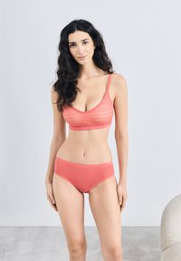 Κοραλί σουτιέν με υφασμάτινη δαντέλα και ρυθμιζόμενους ιμάντες, σε συνδυασμό με ομαλά κοραλί σλιπ με ραβδωτό σχέδιο και ελαστική ζώνη στη μέση.
