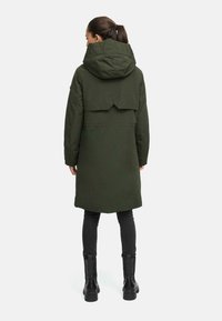 Veste parka verte avec capuche, conçue avec un col montant et un dos à plusieurs couches. Dispose d'une texture lisse et d'une coupe mi-longue.