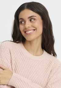 Ljusrosa stickad tröja med ett strukturerat, diagonalt mönster och ribbad krage. Har långa ärmar och en avslappnad passform.