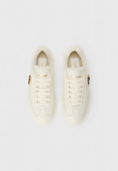 Off-white lace-up sneakers with gold "roberto cavalli" branding, plush lining, and gold lion head embellishment on the sides.