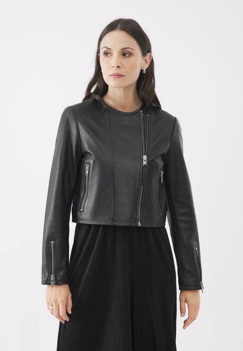 Giacca cropped in pelle nera con chiusura a zip, due tasche laterali e maniche lunghe con dettagli a zip sui polsini.
