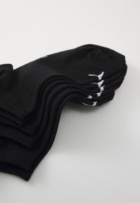 Schwarze Sportstrümpfe ordentlich auf einem Stapel gestapelt, mit geripptem Muster, weichem Material und einem weißen Logo auf der Oberseite jeder Socke.