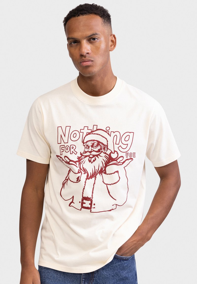 T-shirt de algodão creme com estampa vermelha do Pai Natal e o texto "Nada para ti." Mangas curtas e design clássico com gola redonda.