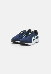 Baskets de sport bleu marine avec tige en maille, semelle intermédiaire blanche et semelle extérieure noire. Comprend des accents verts et un système de laçage pour un maintien sécurisé.