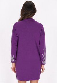 Violetti neulemekko pitkillä hihoilla, joissa on hopeista brodeerausta koho- ja hihansuissa, ja hieman rento siluetti. Teksturoitu kangas pehmeällä pinnalla.