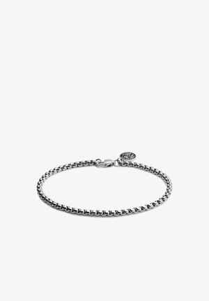 Sølvkjedearmbånd med sammenkoblede ledd, utstyrt med en krabbe-lås og en sirkulær charms med logo. Glatt metallisk finish.