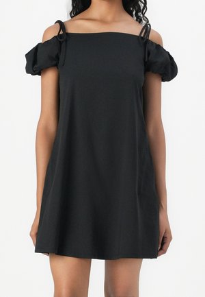 Czarna sukienka odkrywająca ramiona z bufkami, wykonana z miękkiego materiału. Posiada regulowane wiązania na ramionach i luźny fason.