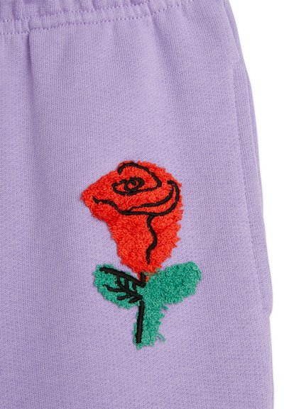 Lavender fabric featuring an embroidered red rose with textured petals and green leaves, outlined in black stitching.