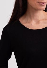 Svart ribbad tygtröja med rund halsringning. Slät yta, åtsittande design och långa ärmar, som visar en enkel och klassisk stil.