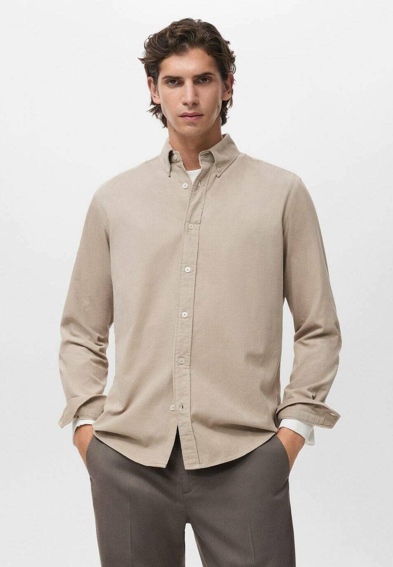 Camisa abotonada beige de mangas largas, hecha de una tela suave. Presenta un cuello clásico y un ajuste holgado. Diseño liso, con un detalle mínimo.