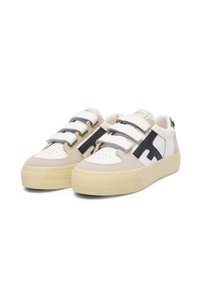 Baskets avec des panneaux beiges, noirs et blancs, dotées de trois sangles Velcro, d'un bout arrondi et d'une épaisse semelle en caoutchouc jaune.