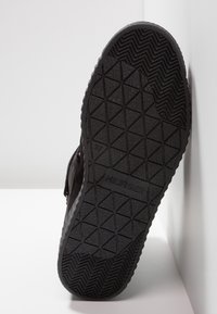 Musta lenkkarin pohja, jossa on teksturoitu kuvio, joka sisältää timantti- ja kalanruotokuvioita. Mukana "HILFIGER"-logo ja koko 37 kaiverrettuna.