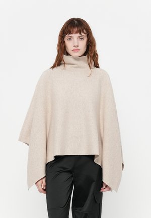 Beige uldblanding poncho med høj funnel-krave, brede ærmer og en afslappet silhuet, kombineret med sorte bukser. Glat tekstur, uden mønstre.
