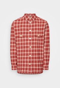 Czerwono-biała koszula flanelowa w kratkę z kołnierzykiem button-down, długimi rękawami i dwiema kieszeniami na piersi. Posiada kremowe guziki.