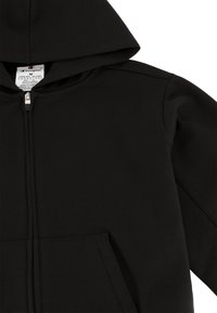 Hoodie noir zippé en tissu doux, avec une poche kangourou, une capuche à cordon de serrage et une étiquette près de l'encolure. Texture lisse.