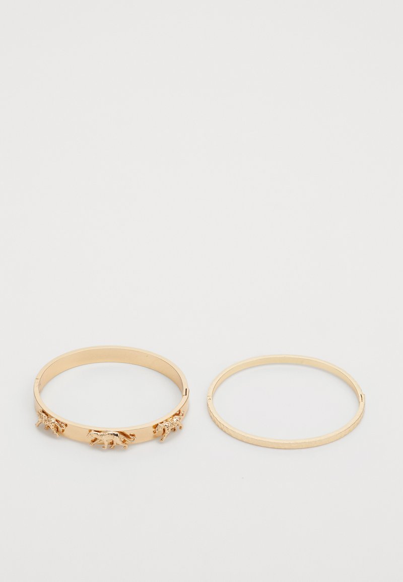 Ensemble de deux bracelets en métal doré. L'un présente une surface texturée avec des accents animaliers ; l'autre est lisse et simple dans son design.