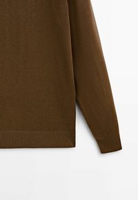 Maglione marrone a maglia con polsini e orlo a costine, che mette in mostra un tessuto texturizzato con una finitura liscia. Vista ravvicinata del dettaglio della manica.