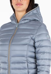 Giacca puffy azzurro chiaro con cappuccio, caratterizzata da imbottitura trapuntata orizzontale, zip completa e dettaglio del logo sulla manica sinistra.