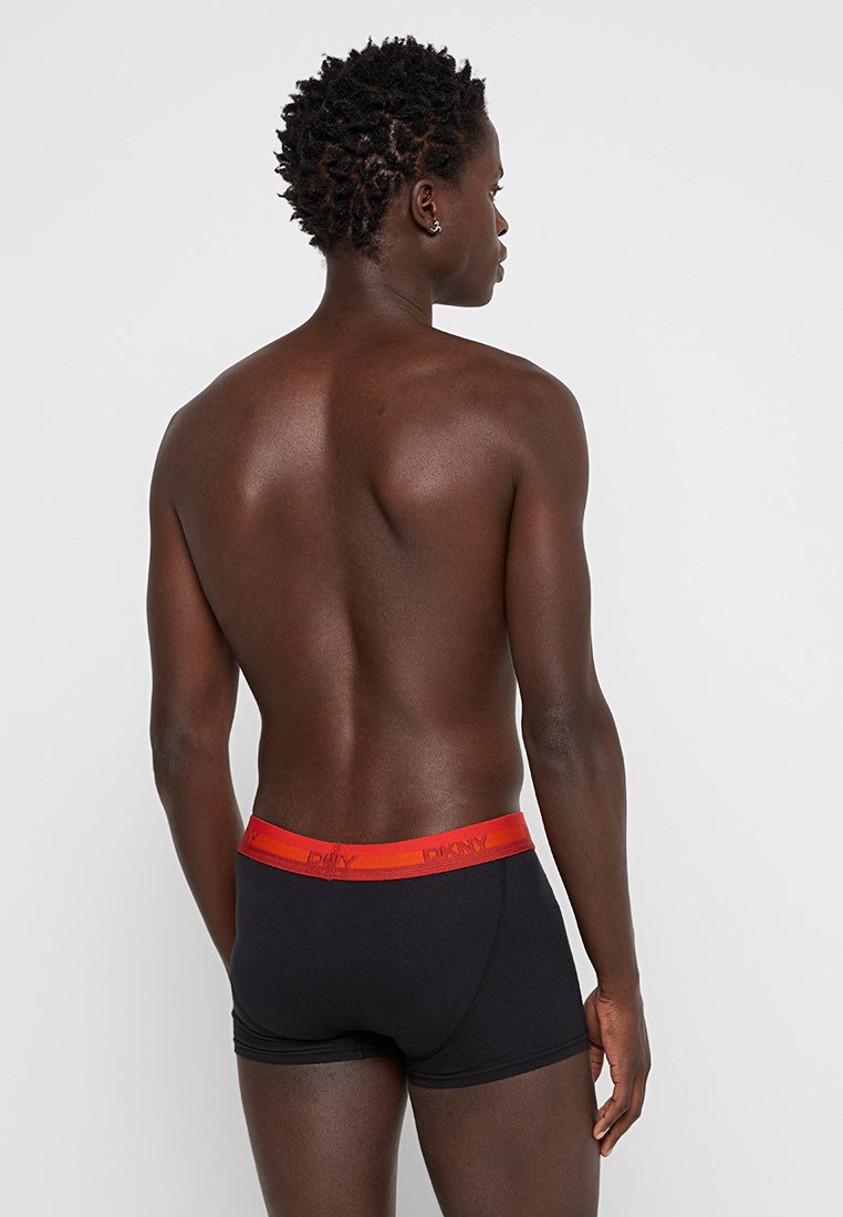 Czarne bokserki z jasnoczerwoną elastyczną talią z brandingiem. Tkanina wydaje się gładka, a fason jest dopasowany.