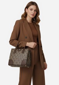 Borsa marrone con texture, caratterizzata da un esterno decorato con motivo e dettagli in pelle marrone scuro. Ferramenta dorata sui manici e alla base aggiunge particolari.