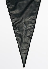 Tessuto triangolare in pelle nera con una texture liscia, caratterizzato da una stretta apertura a fessura. I bordi sono leggermente curvi, creando una forma affusolata.