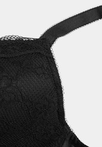 Sort blonde-bh med blomsterprint og meshstruktur. Har justerbare stropper og en glat kant. Nærbillede med fokus på stofdetaljer.