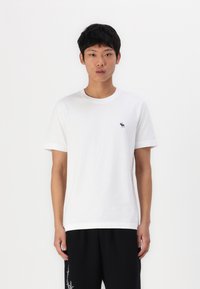 T-shirt bianco in cotone con scollatura a girocollo e maniche corte. Piccolo logo blu navy sul lato sinistro del petto. Tessuto liscio, vestibilità comoda.