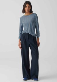 Gestreifte Langarmbluse in Blau und Weiß, kombiniert mit hochtaillierten, weit geschnittenen, marineblauen Hosen. Weicher Stoff, lockere Passform, legere Styling.