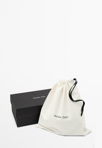 Borsa in cotone con coulisse di colore bianco sporco e corda nera, con logo "Massimo Dutti"; scatola rettangolare nera sottostante.