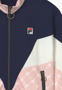 Giacca con zip navy e bianca con accento rosa, dotata di toppa con logo e tasche laterali con zip, realizzata in tessuto liscio con una finitura testurizzata.