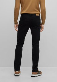 Jeans negros de corte slim, confeccionados con una mezcla de algodón; cuentan con cinco bolsillos, parche de cuero con logo en la cintura y costuras mínimas.