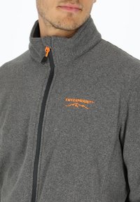 Gray fleece jacket featuring a high collar, black zipper, and orange accents. Logo "SWEDEMOUNT" embroidered in orange on the chest.