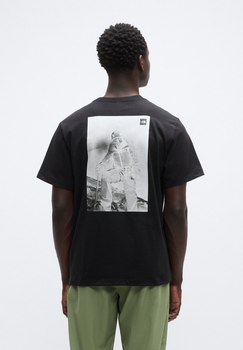 Μαύρο βαμβακερό t-shirt με μεγάλο μονόχρωμο γραφικό τύπωμα στην πλάτη, με μικρό λογότυπο στην πάνω γωνία.