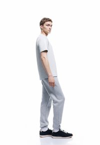 Grijze katoenen t-shirt met korte mouwen en bijpassende grijze joggingbroek. Zwarte sneakers met witte zolen en veters. Eenvoudig ontwerp, comfortabele pasvorm.