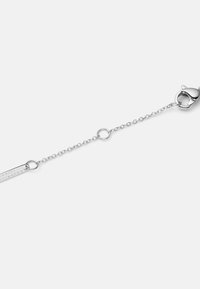 Bracciale in metallo argento con design a catena, chiusura a moschettone e un'etichetta rettangolare con il testo "DANIEL WELLINGTON."