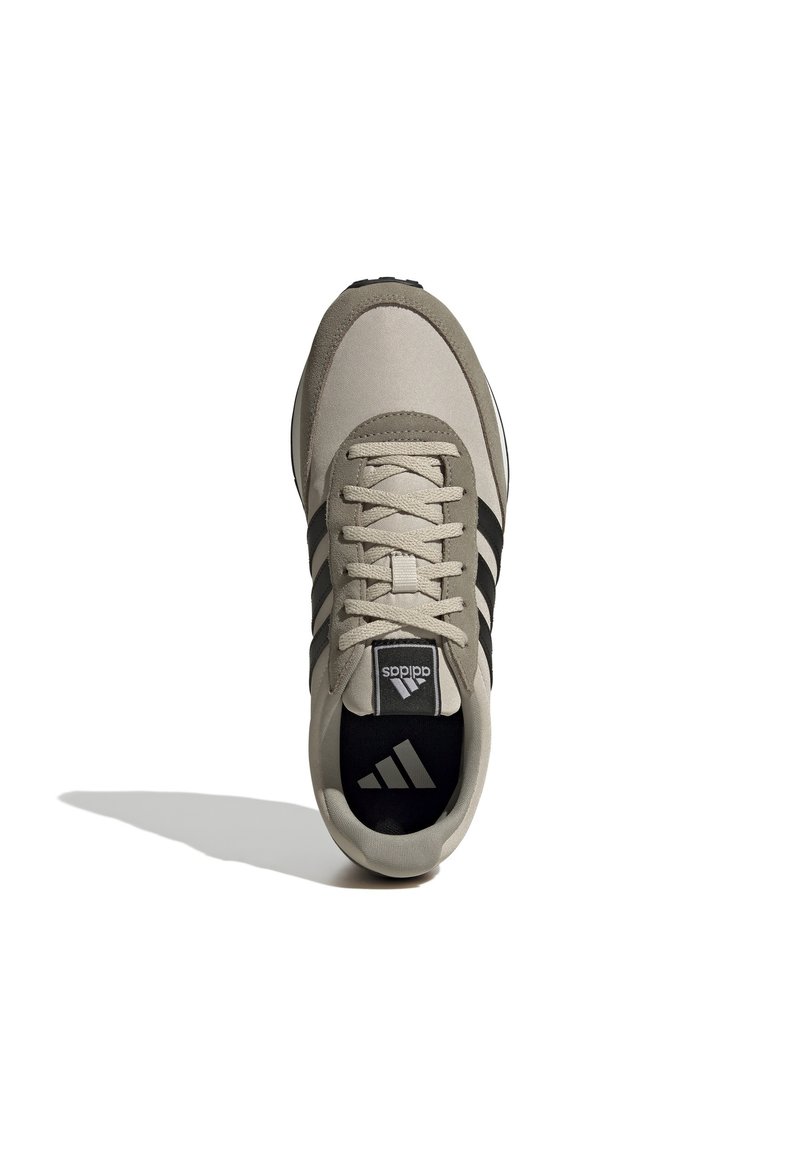 Beige sport schoen met zwarte strepen, ronde neus, vetersluiting en textielstof. Heeft een zwarte binnenzool met logo.