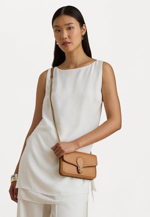 Tan läder crossbody-väska med klaffstängning, guldfärgad utsmyckning och en texturerad yta. Bärs med en vit ärmlös topp.