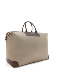 Sac fourre-tout beige avec une surface lisse, accents en cuir texturé marron à la base et aux poignées, et une forme rectangulaire. Fermeture éclair.
